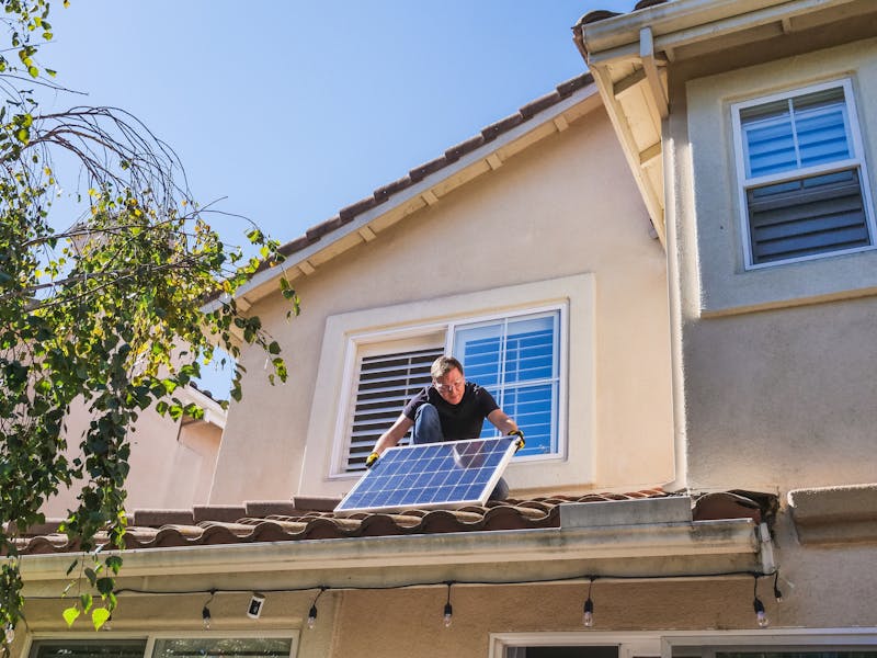 A Man Inspecting a Photovoltaic Panel on the Roof