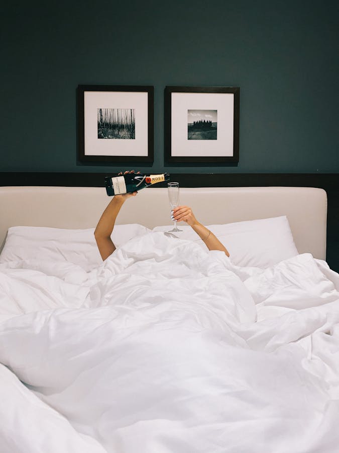 Woman Pouring Champagne in a Bed