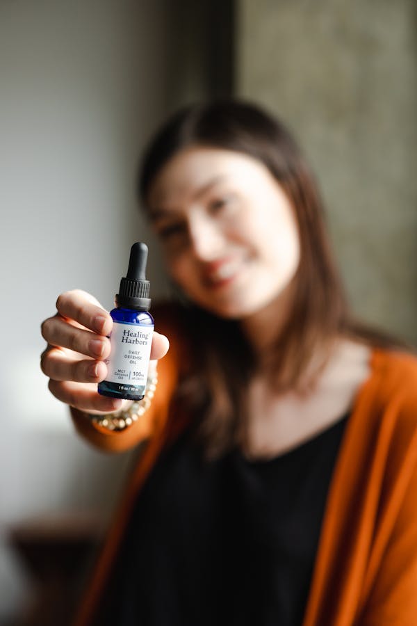 A Woman Holding a Bottle of CBD Oil in a Bottle