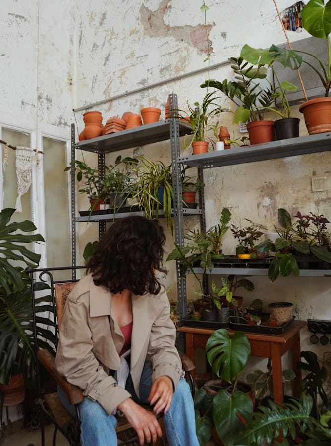 A woman sitting in front of a shelf full of plants