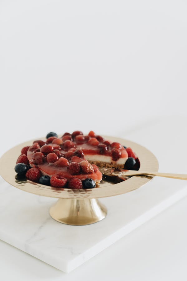 A tempting cheesecake adorned with fresh berries elegantly presented on a gold cake stand.