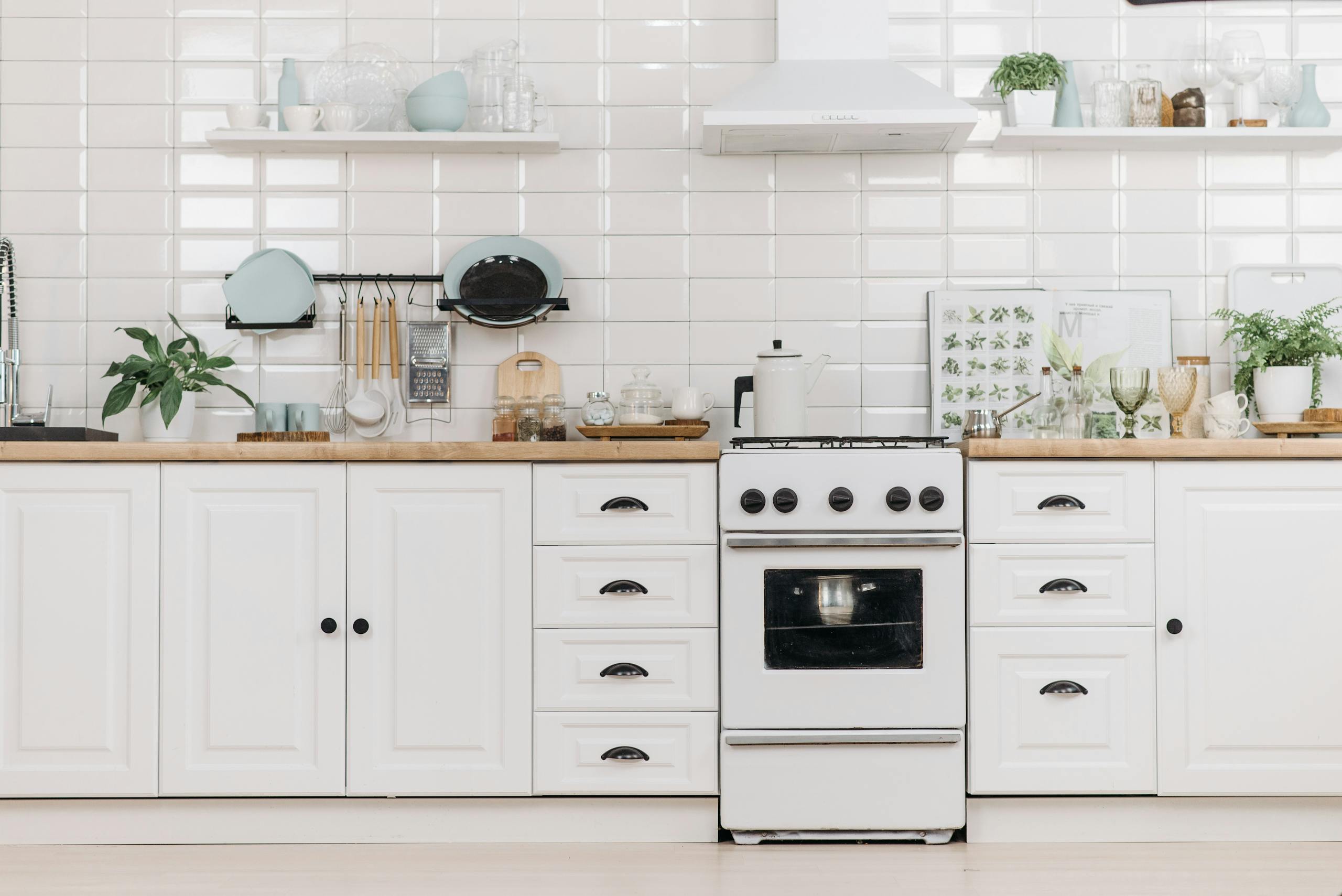 Bright minimalist kitchen with white cabinets and stove, offering a clean and organized look.