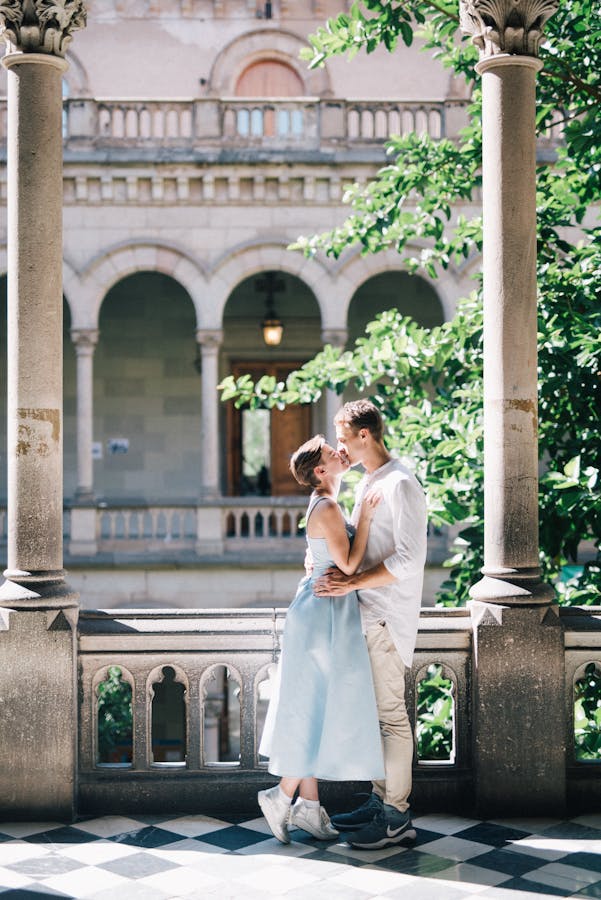 Couple embracing under historic arches, capturing love and architecture.