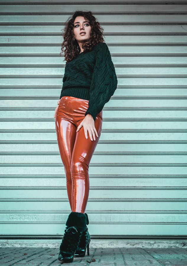 Fashionable woman posing in shiny leggings against roller shutter in Istanbul.