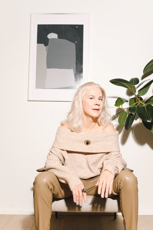 Stylish senior woman sitting indoors, exuding elegance and fashion.