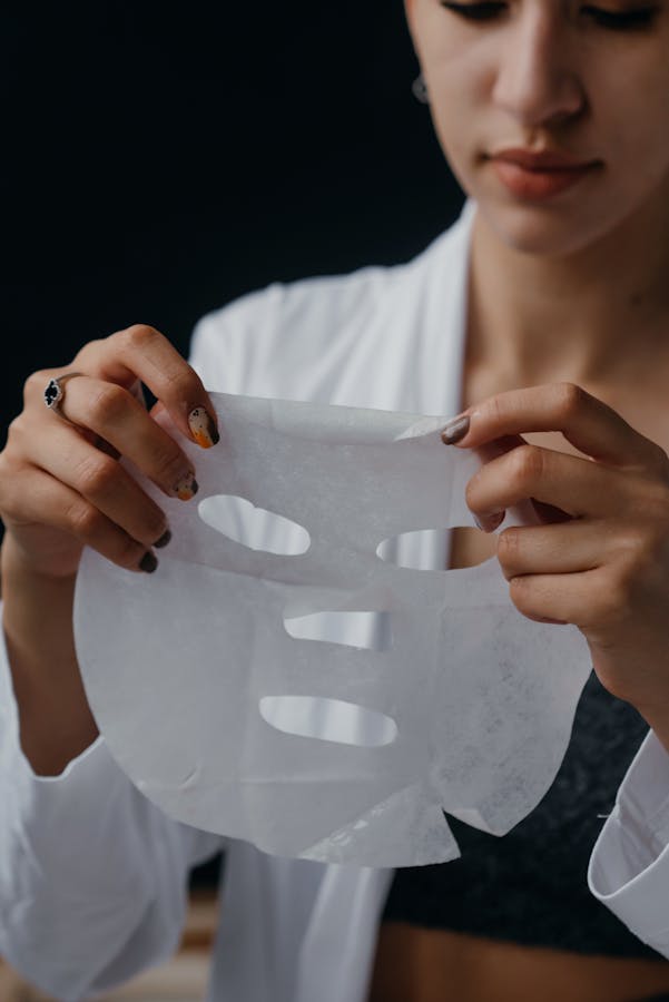 Close-up of a woman holding and preparing to apply a moisturizing sheet mask, focusing on skincare routine.
