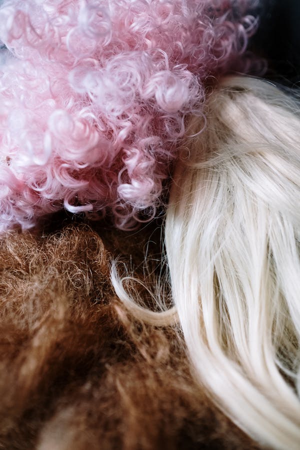 Close-up of various colorful wigs, showcasing textures and shades in vibrant detail.