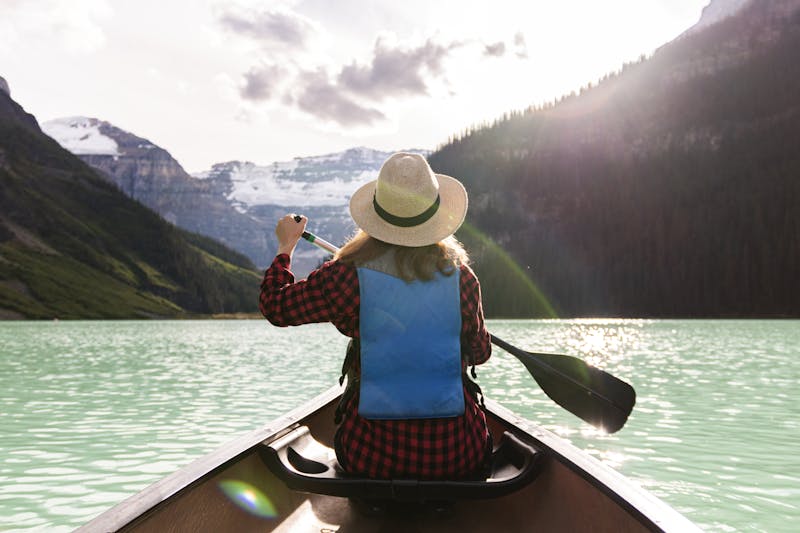 Woman paddles canoe in Lake Louise, enjoying a peaceful summer adventure.