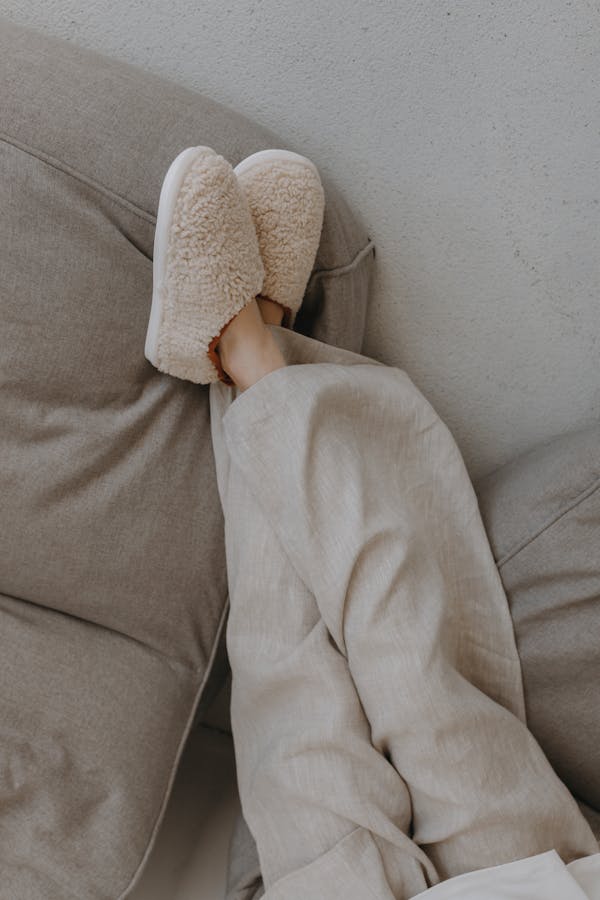 Relaxed person lounging indoors with plush slippers and winter pajamas, conveying warmth and comfort.