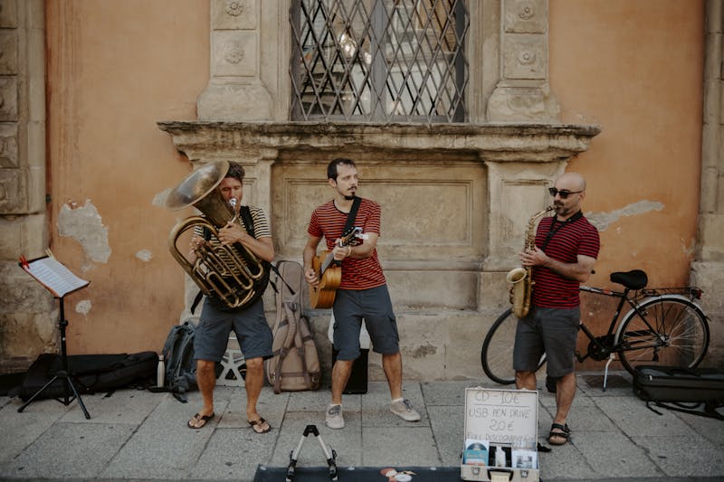 Three musicians busking with tuba, guitar, and saxophone on a city street.
