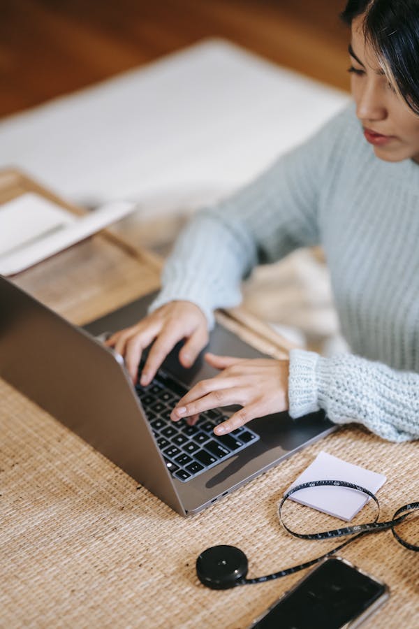 A woman focusing on her laptop, working remotely in a cozy indoor setting.