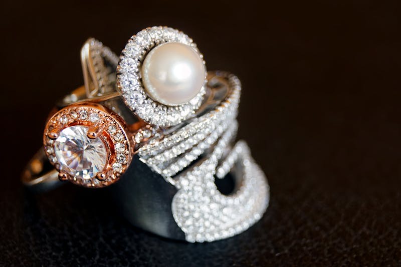 Close-up of luxurious pearl and diamond rings with gold accents on a black background. 2025 oscars