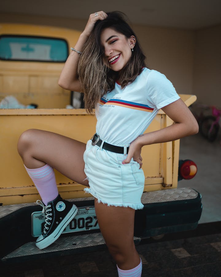 Smiling woman in casual attire posing by a vintage truck, exuding joy and style. styling crew socks