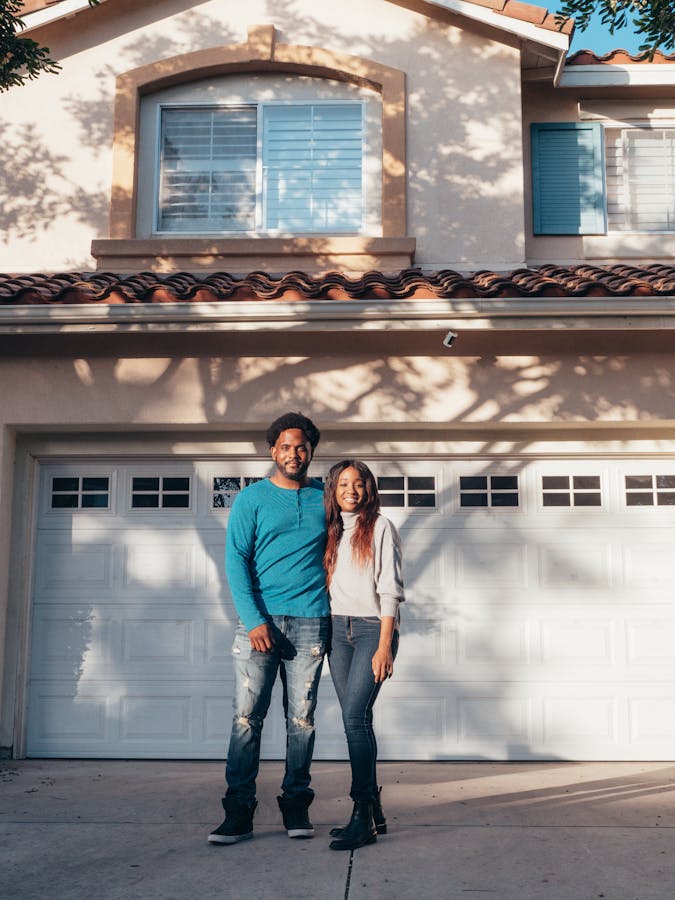 A joyful couple stands in front of their newly purchased home, symbolizing togetherness and success.